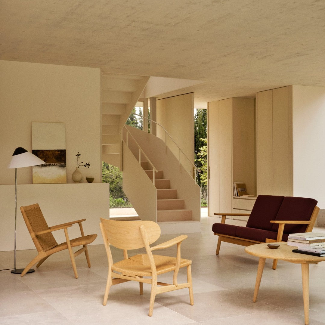 Modern living room featuring warm wooden tones, deep burgundy accents, and soft beige walls, creating a cozy ambiance.