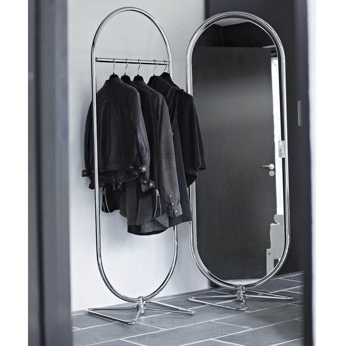 "Elegant chrome clothing rack with black garments against a sleek monochrome background."