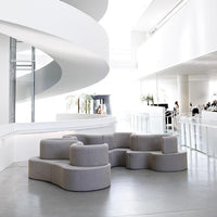 Modern gray modular sofa with smooth, rounded edges, set against a bright white interior.