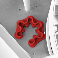 Curvy red sofa with a unique wave pattern, set against a minimalist gray floor. Stylish and modern design.