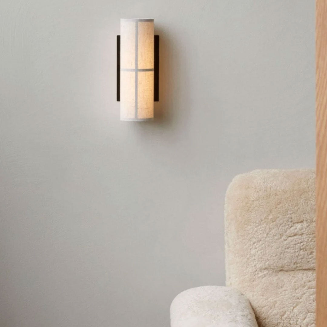 Modern wall sconce in white and warm beige with black accents, featuring a sleek, minimalist design.