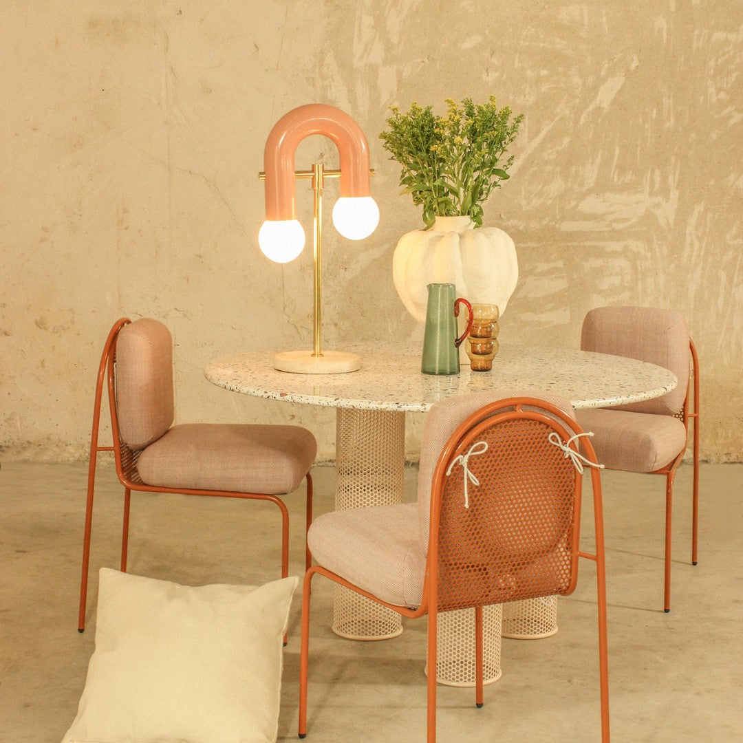 Modern dining set featuring pastel pink and cream colors, with a marble tabletop and textured chair patterns.
