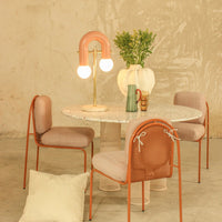 Modern dining set featuring pastel pink and cream colors, with a marble tabletop and textured chair patterns.