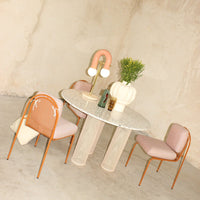 Modern round table with a speckled top and pastel pink chairs, featuring soft curved patterns and earthy tones.