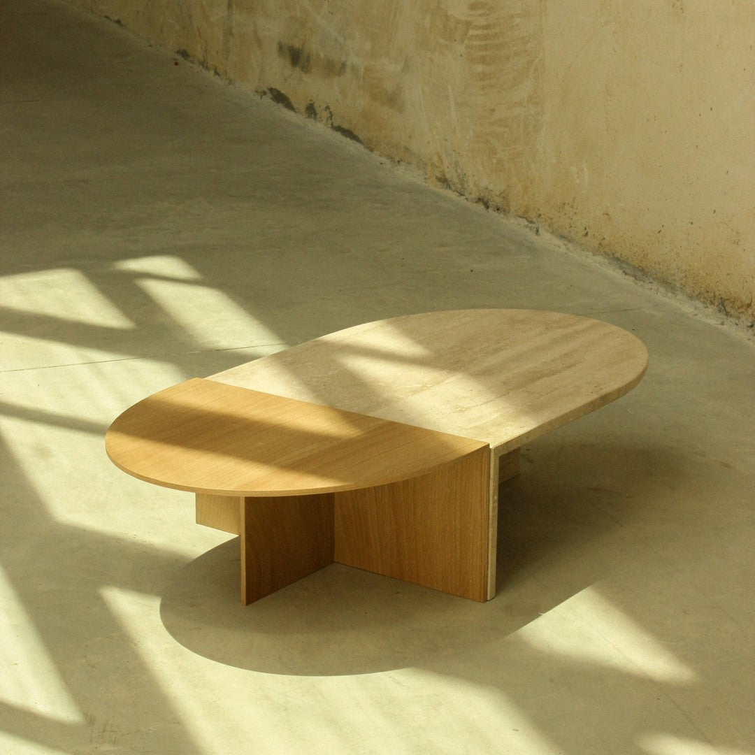Light wood coffee table with a smooth, oval top and geometric base, featuring neutral tones and a minimalist design.