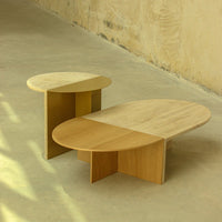 Two modern coffee tables featuring a natural wood finish with contrasting light and dark tones, showcasing sleek, curved shapes.
