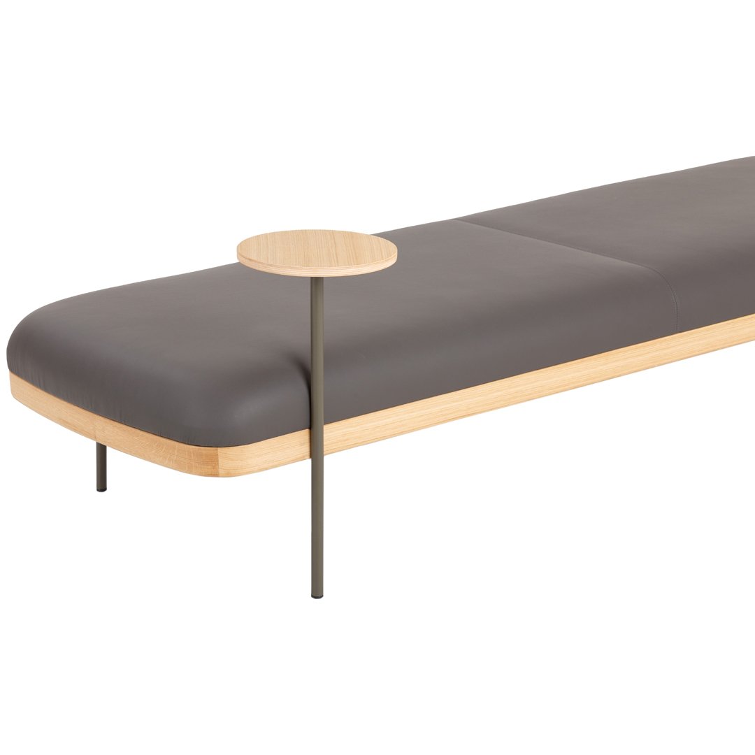 Gray upholstered bench with a light wood base and round side table, featuring a minimalist modern design.