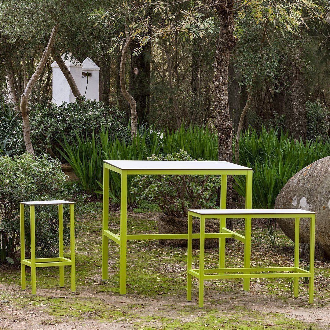 Set of three outdoor tables in vibrant lime green with sleek, modern designs against a natural backdrop.