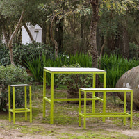 Set of three outdoor tables in vibrant lime green with sleek, modern designs against a natural backdrop.