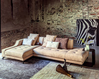 Beige sectional sofa with textured fabric, complemented by neutral and pastel throw pillows, against a rustic brick wall.
