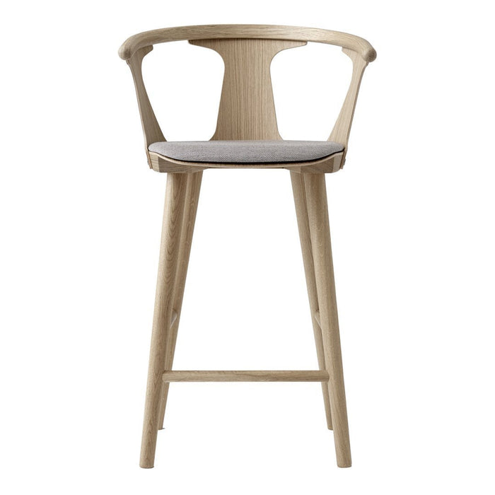 Light oak bar stool with a minimalist design, featuring a curved backrest and soft gray cushion.
