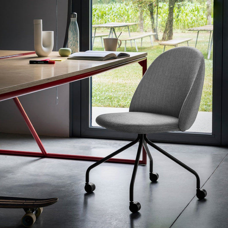 Gray fabric office chair with a curved backrest, set on a black wheeled base, against a modern, bright workspace.