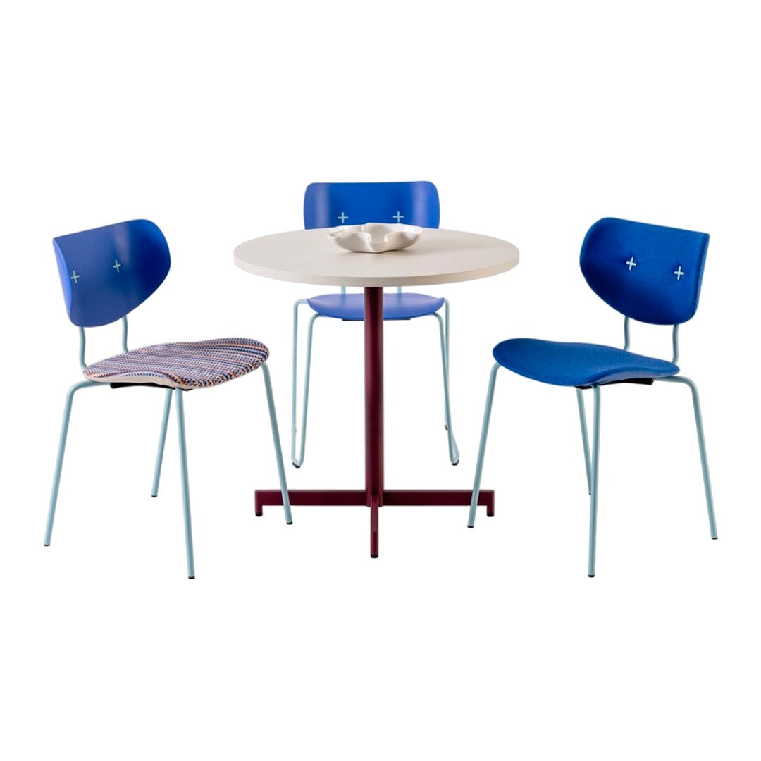 Blue and white patterned chairs with a round cream table and burgundy base, creating a vibrant dining set.