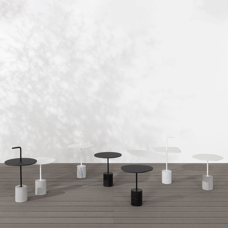 Minimalist black and white tables with sleek designs and circular tops on a wooden deck.