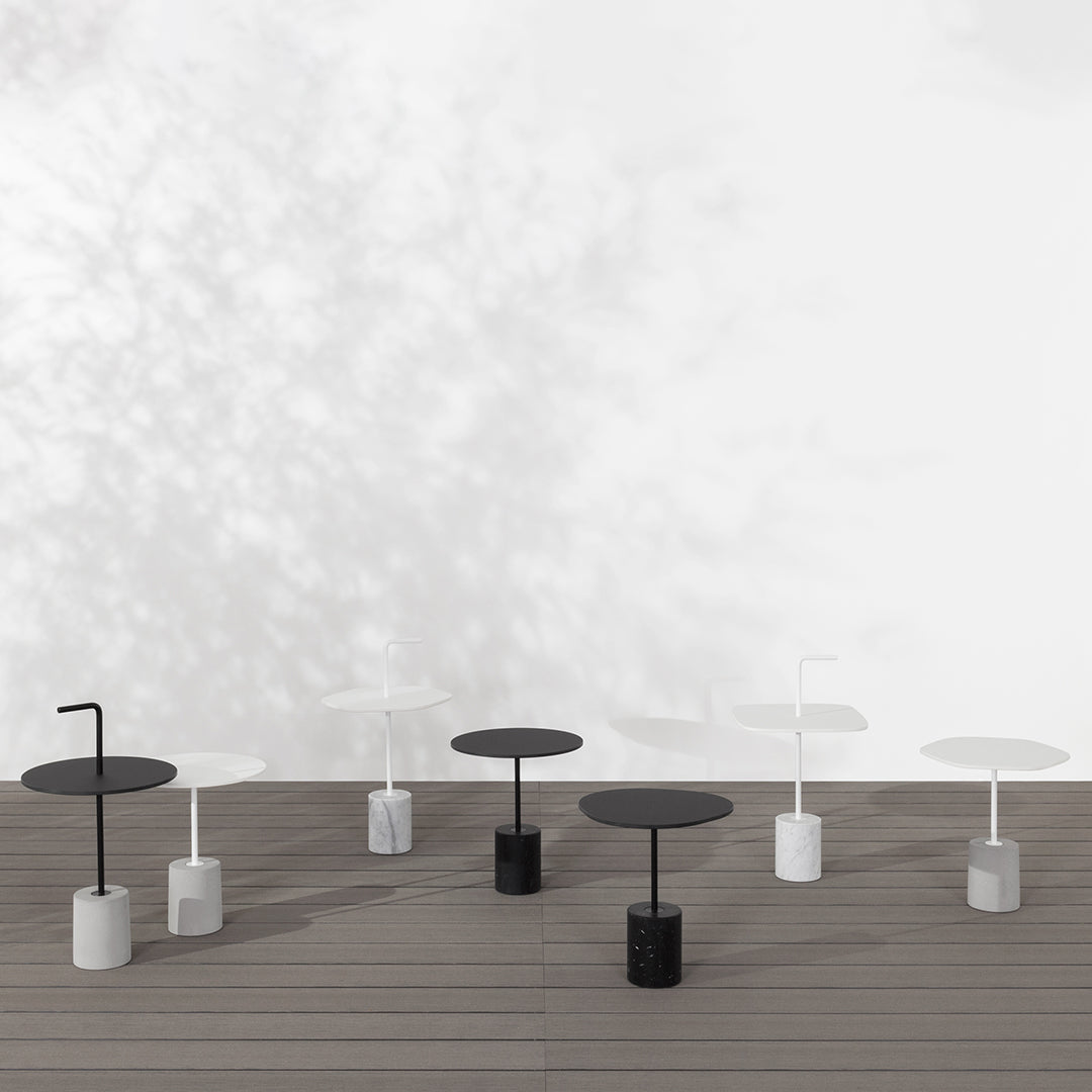 Modern tables in black and white with sleek bases, featuring minimalist design and geometric patterns.