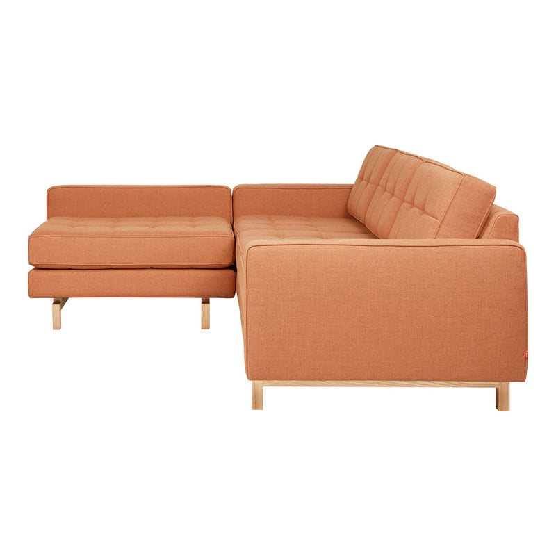 Modern L-shaped sofa in warm terracotta fabric with a minimalistic design and natural wood legs.