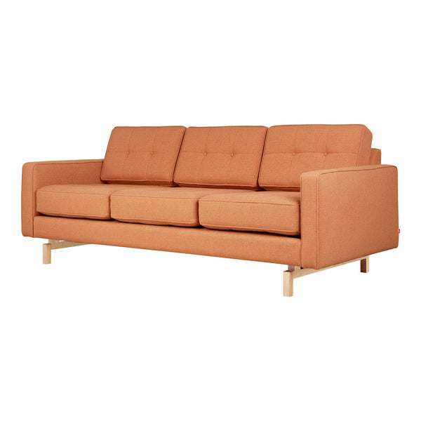 Rust-orange fabric sofa with modern design, featuring three tufted cushions and light wood legs. Ideal for stylish interiors.