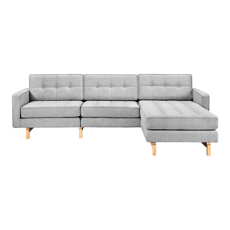 Light gray tufted sectional sofa with wooden legs, featuring a modern and minimalist design.