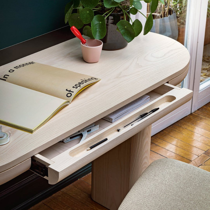 Light wood desk with a smooth, rounded surface; minimalist design featuring earthy tones and subtle textures.