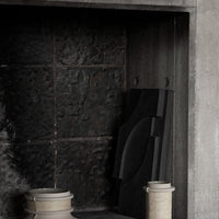 "Textured black backdrop with light-colored ceramics and a geometric black design element."