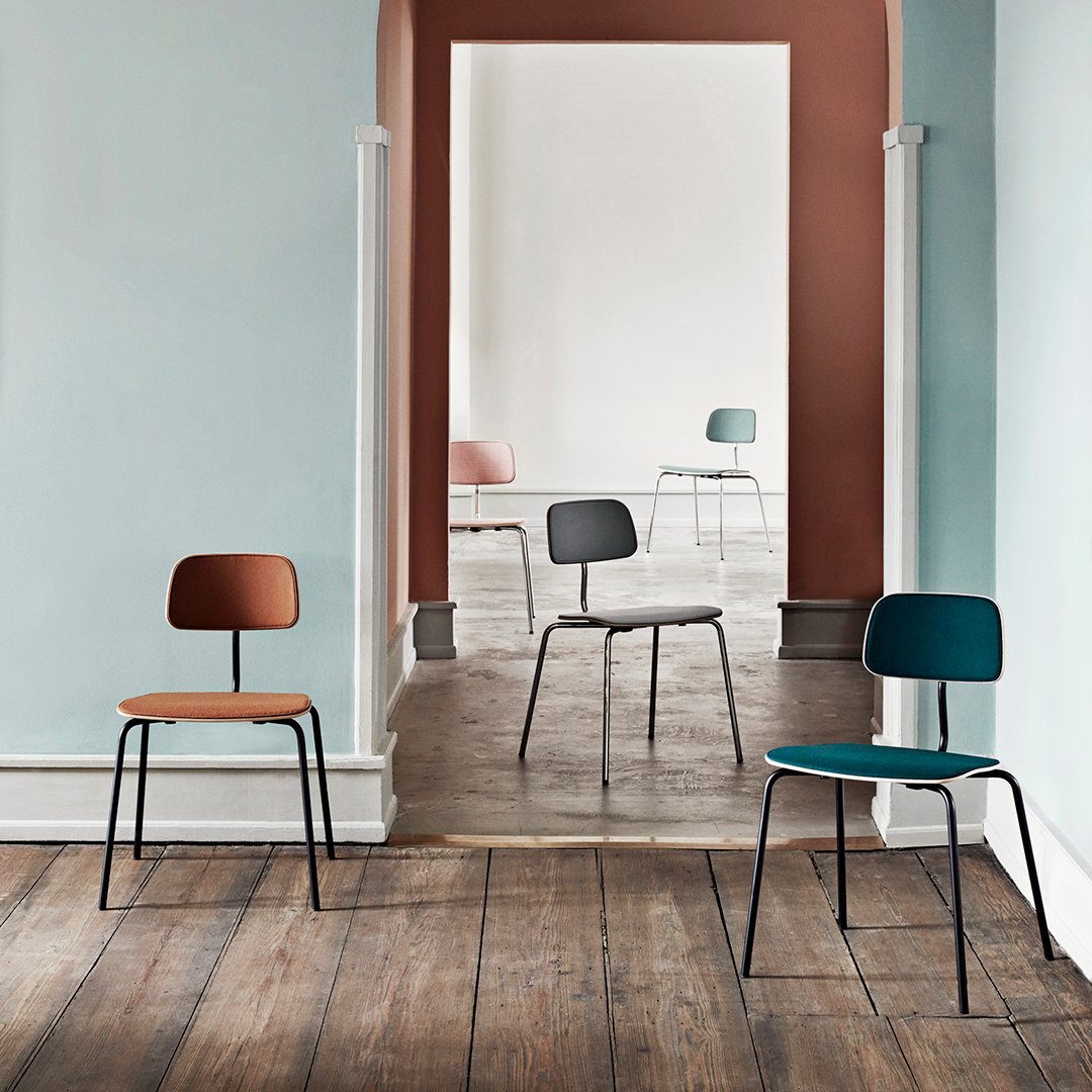 Colorful modern chairs in earthy tones of brown, green, and soft pastels against a minimalist backdrop.