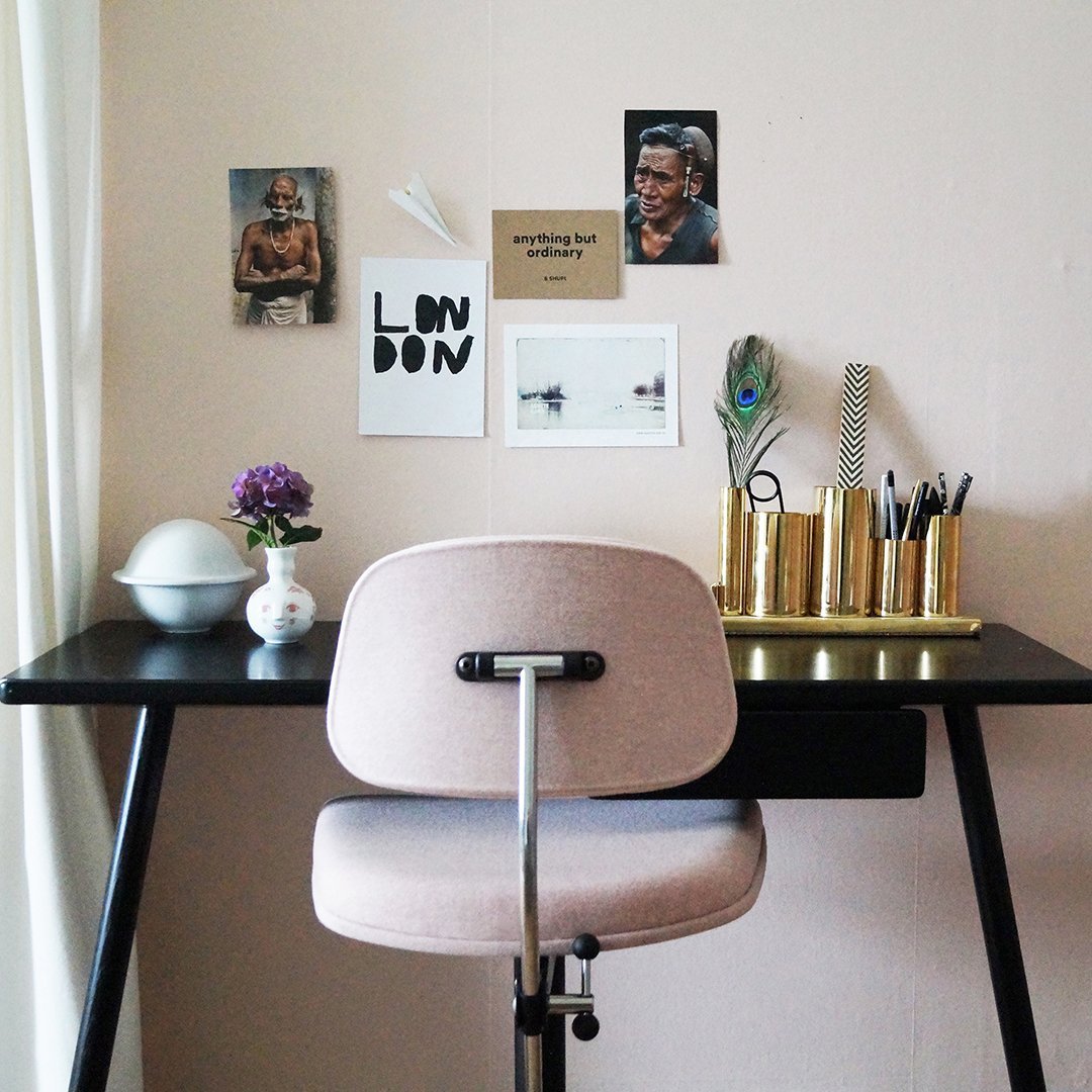 Pink chair against a black desk, featuring gold and white decor elements with a soft, neutral background.