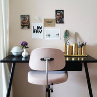 Pink chair against a black desk, featuring gold and white decor elements with a soft, neutral background.
