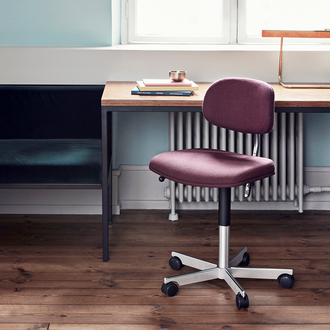 Plum upholstered office chair with a smooth, minimalist design on a light wood and black color palette.