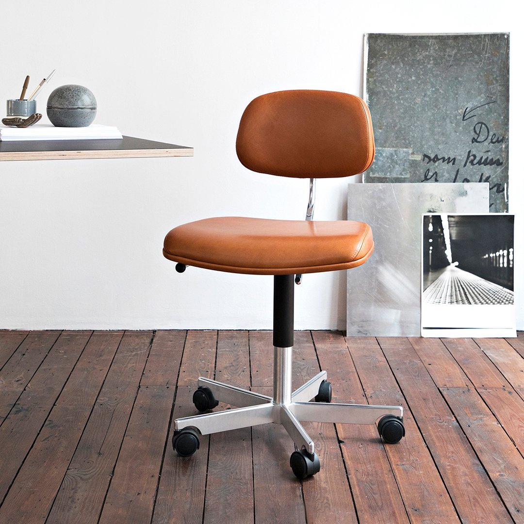 Brown leather office chair with a sleek, minimalist design and chrome base on wooden floor.