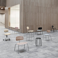 Colorful chairs in various hues, including pastel pink, blue, black, and natural wood, arranged in a modern setting.
