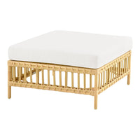 Square rattan coffee table with a natural finish and a plush white cushion on top for a minimalist look.