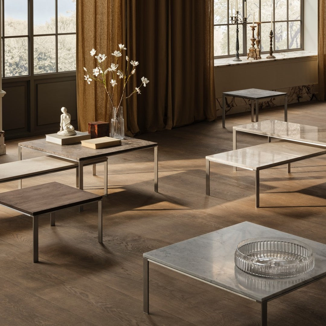 Modern coffee tables with sleek metal frames, featuring wood and glass surfaces in neutral tones and elegant finishes.