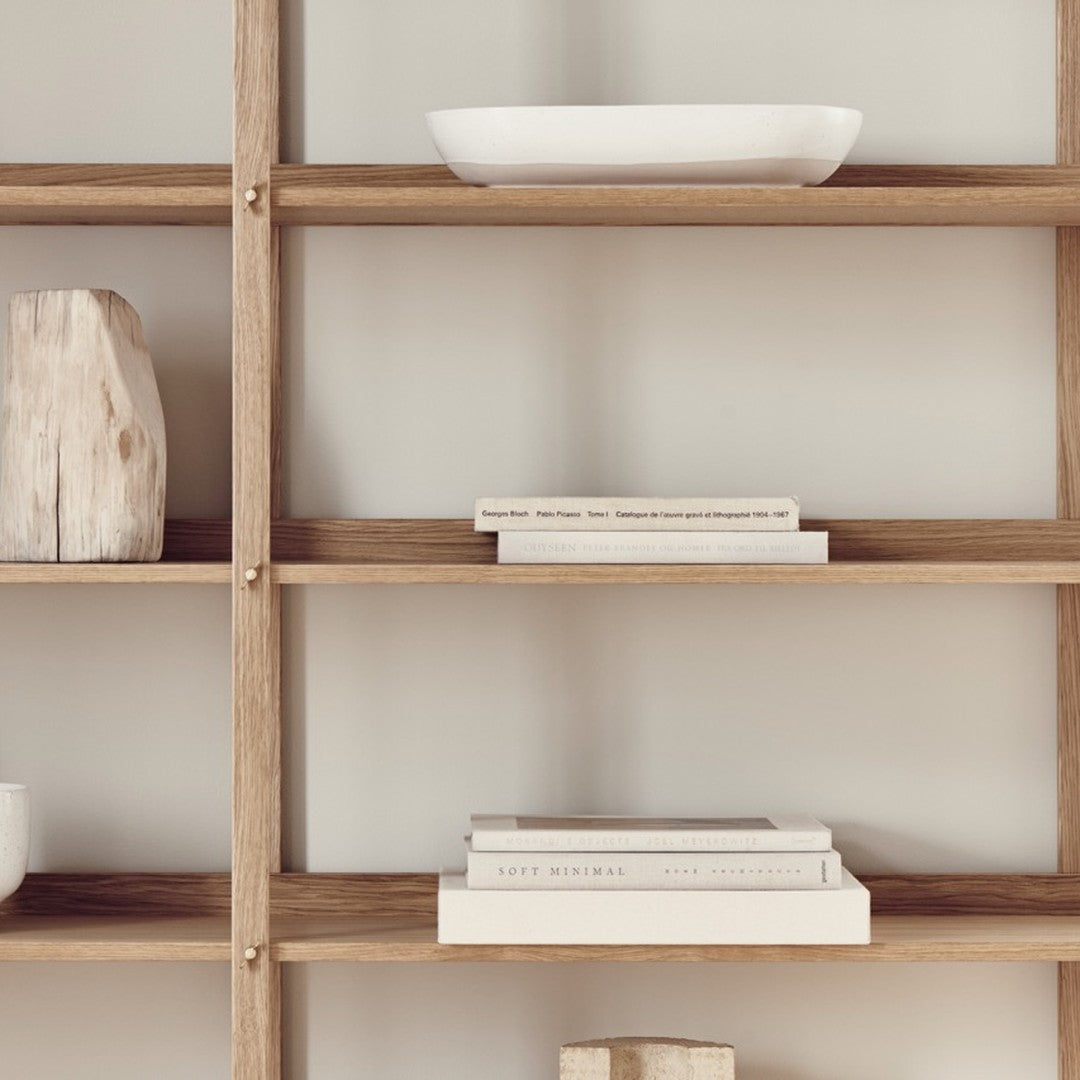 Natural wood shelves with minimalist white decor and neutral-toned books, creating a clean and modern aesthetic.
