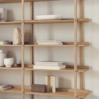 Light wood shelving unit with a natural finish, featuring minimalist decor and soft geometric patterns.