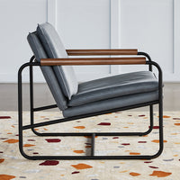Gray upholstered chair with wood armrests, set on a multicolored, abstract patterned rug featuring warm tones.