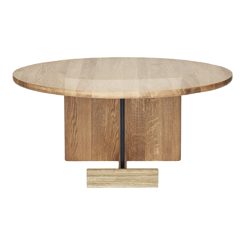 Round wooden dining table with a light oak finish and a smooth surface, featuring a sleek, minimalist base in natural tones.