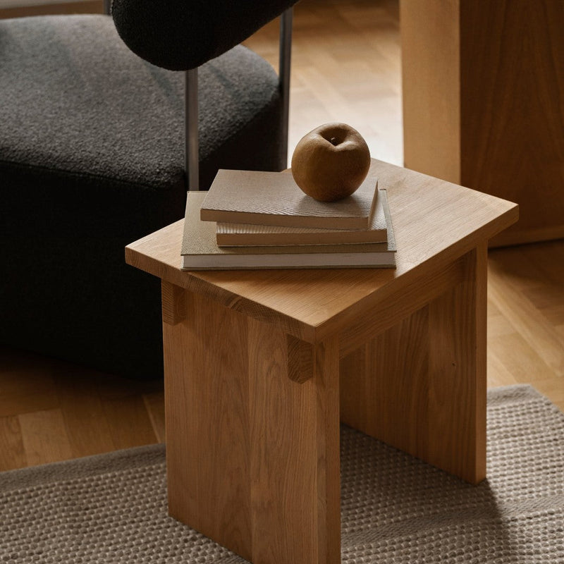 Light wood side table with a smooth finish, complemented by neutral tones and soft textures in the surrounding decor.