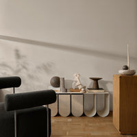 Modern beige and white furniture with rounded edges, accented by black and natural wood elements. Soft, minimalist design.