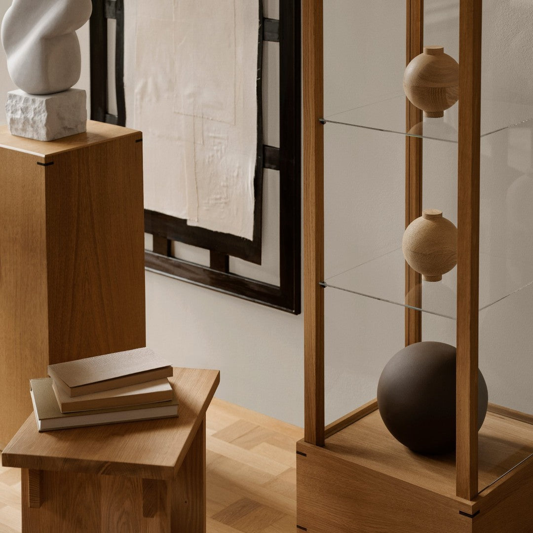 Wooden furniture with natural tones, black accents, and geometric shapes in a minimalist setting.