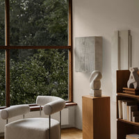 "Soft beige chair with a textured fabric, complemented by natural wood tones and a light gray sculptural accent."