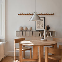 Light wood dining table with minimalist gray pendant lamp, neutral wall decor, and soft beige and cream accents.