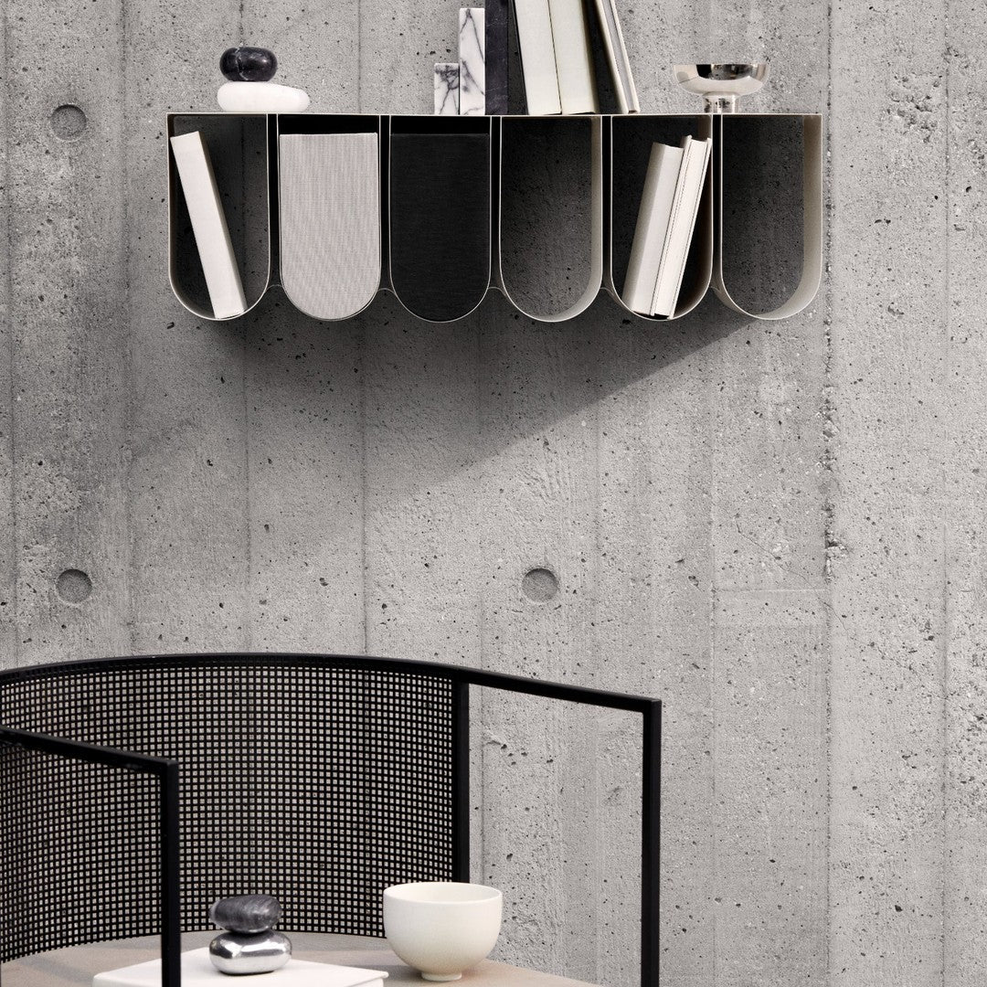 Modern wall shelf in black and gray, featuring curved compartments against a textured concrete wall, minimalist design.
