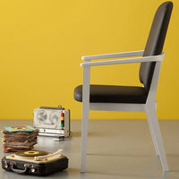 "Stylish black chair with white frame against vibrant yellow backdrop, featuring sleek lines and modern design."