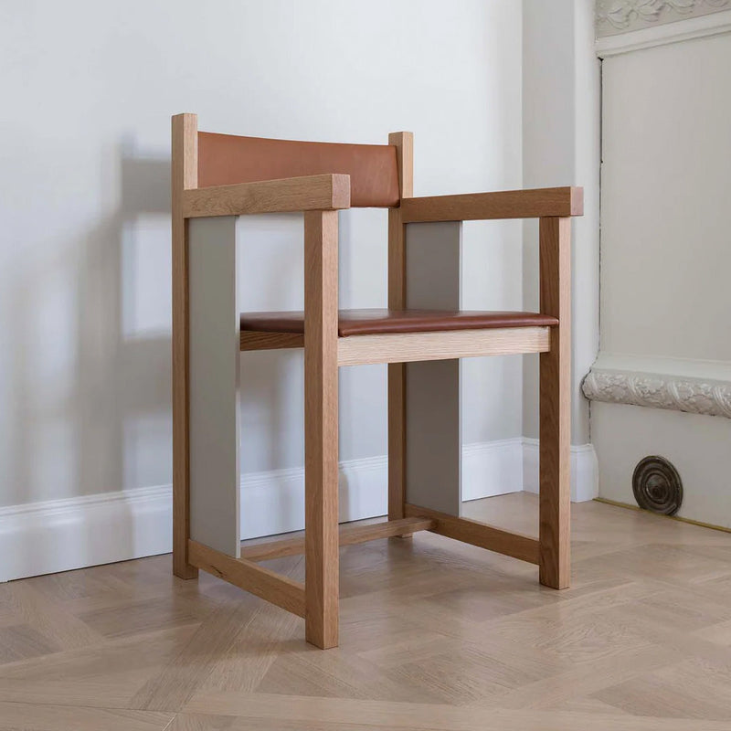 Modern armchair featuring oak frame, tan leather upholstery, and grey accents, creating a stylish, minimalist aesthetic.