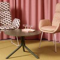 "Geometric patterned chairs in beige, pink curtains, green table, and yellow floor create a vibrant, modern aesthetic."