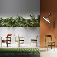 Colorful chairs in red, green, yellow, and beige arranged against a backdrop of lush greenery and a textured rug.
