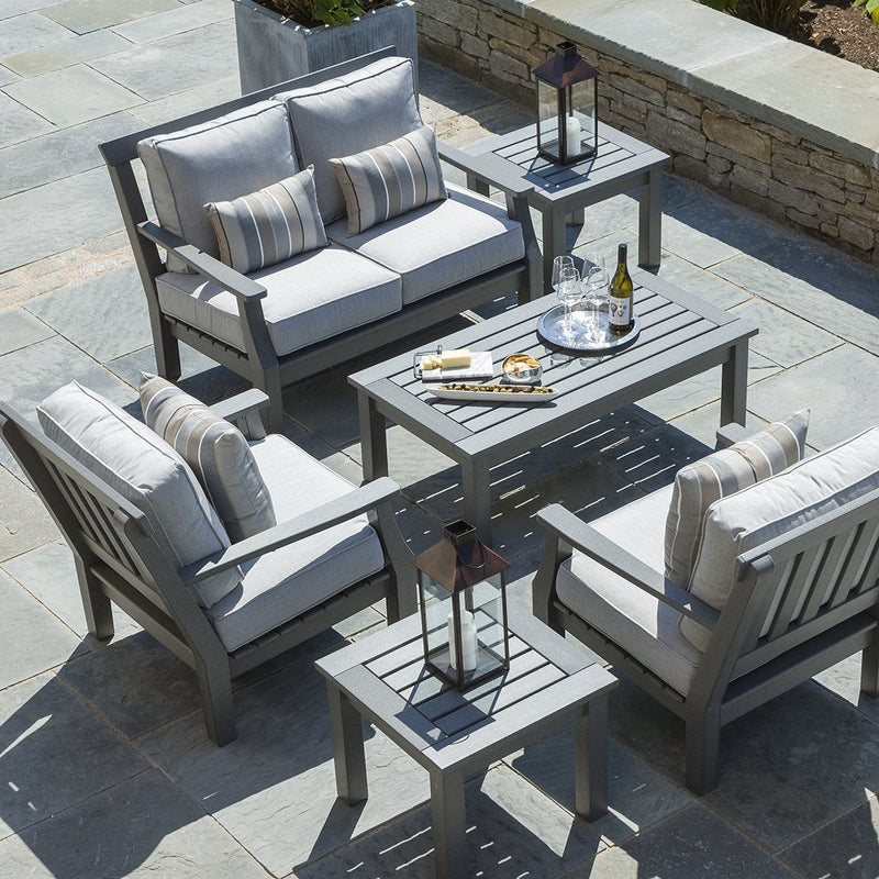 Gray outdoor furniture set with striped cushions and lanterns on a stone patio. Elegant and modern design.