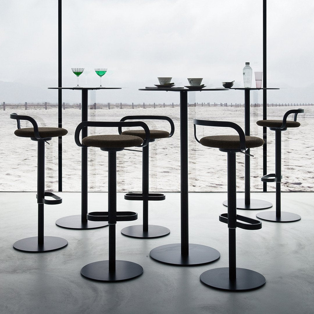 Modern black bar stools with brown seats, set against a minimalist backdrop of a serene beach view.
