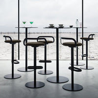 Modern black bar stools with brown seats, set against a minimalist backdrop of a serene beach view.