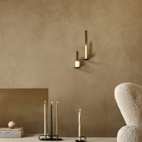 Minimalist wall with tan clay texture, featuring black and cream candle holders, and black and ivory taper candles.